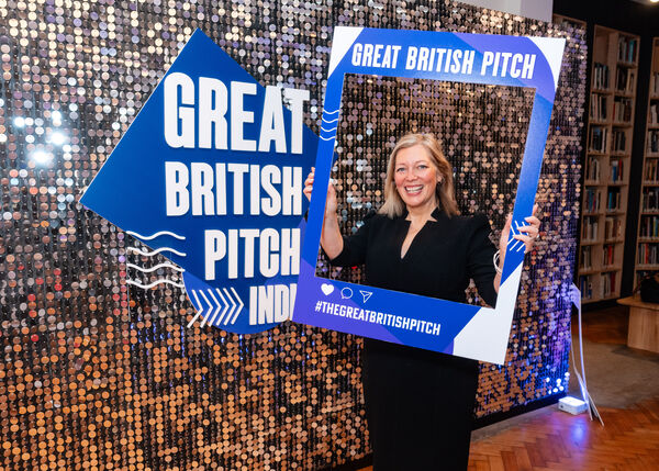A guest holding the Great British Pitch India social media frame in front of the sequin wall